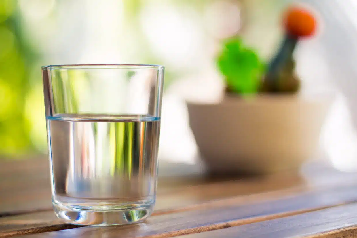 Verre d'eau avec du sel et du vinaigre posé sur une table en bois