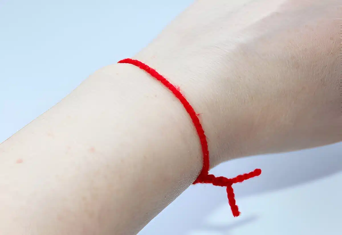 Personne attachant un fil rouge à un poignet