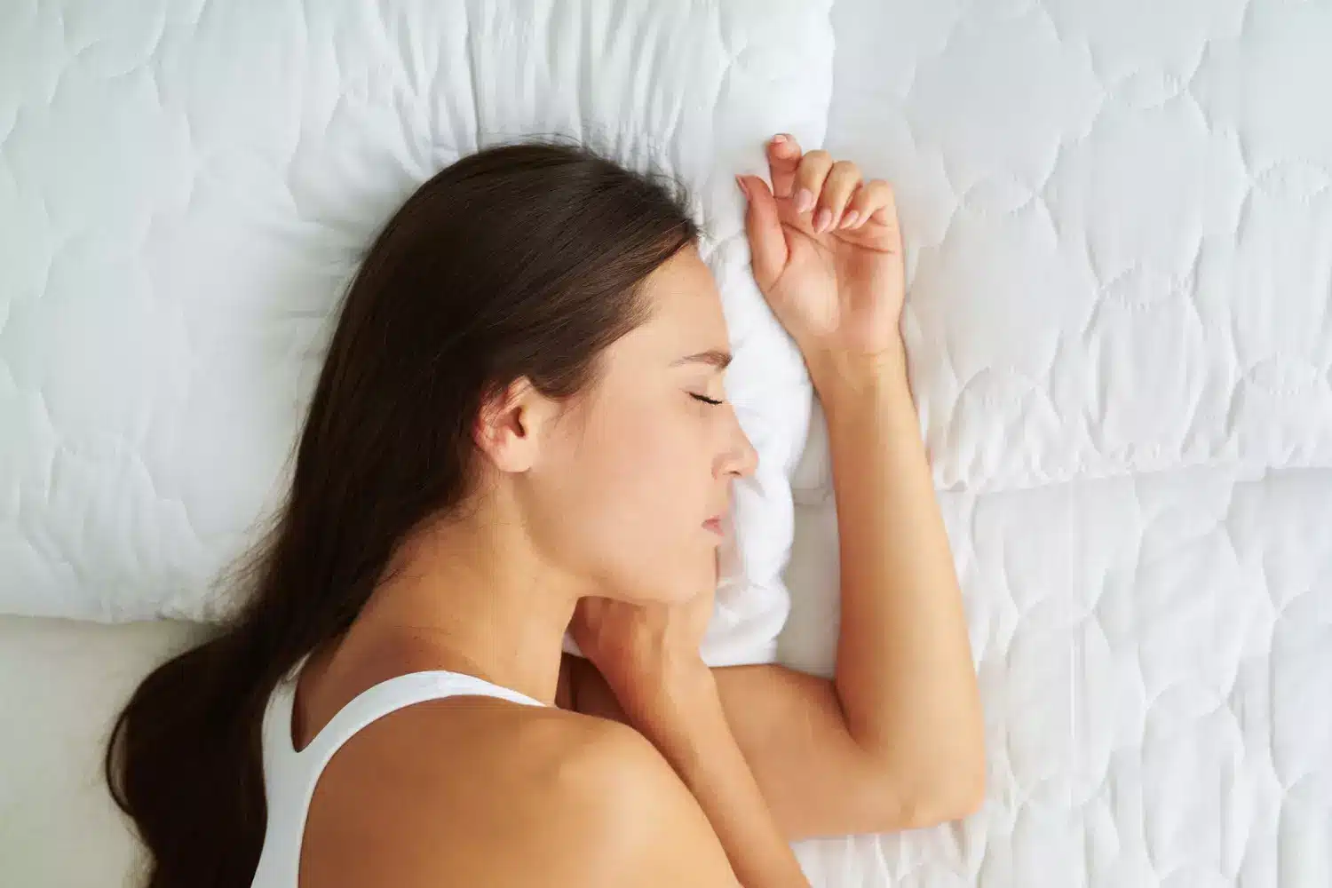 Personne dormant en position fœtale sur le côté, avec un coussin entre les genoux