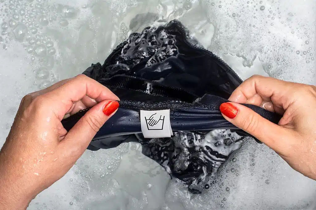 Femme souriante tenant un t-shirt blanc, évoquant le bien-être et la fraîcheur