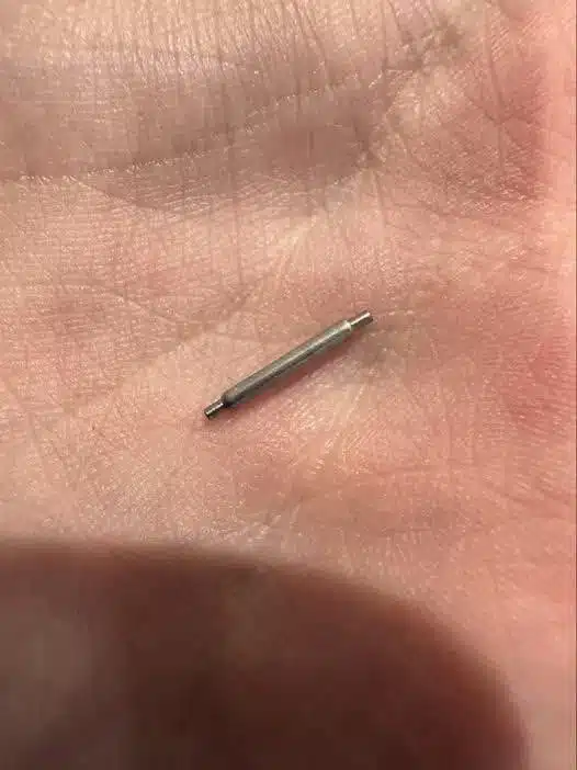 Un petit objet métallique tenu entre deux doigts