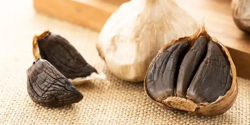 Ail noir bio posé sur une planche en bois