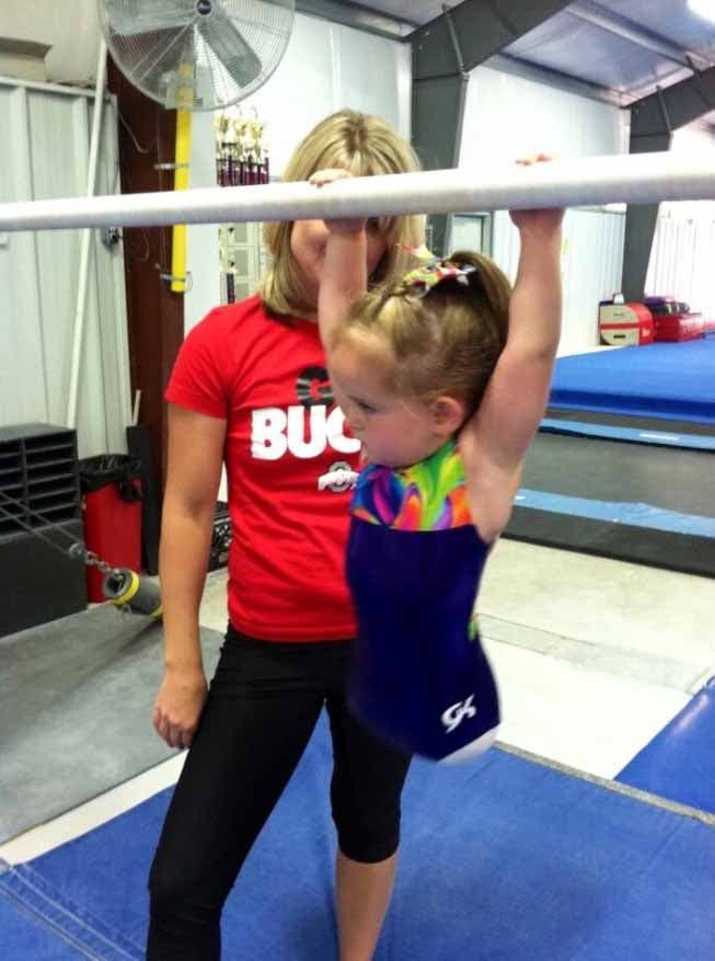 Paige s’aggripant à une barre de gymnastique