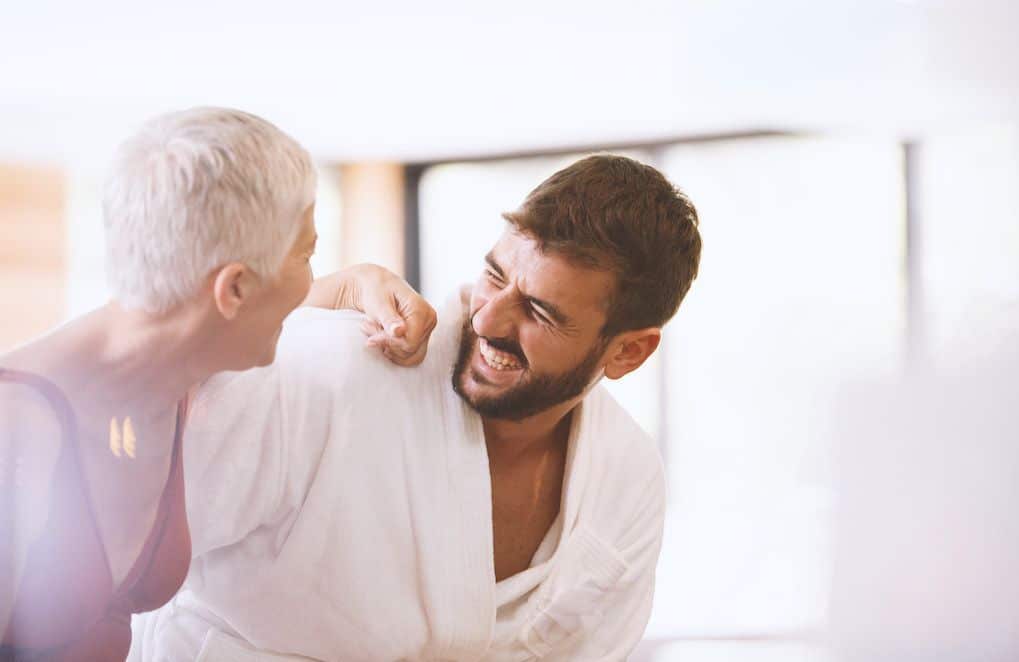 Couple souriant, une femme plus âgée et un homme plus jeune discutant complice dans un café