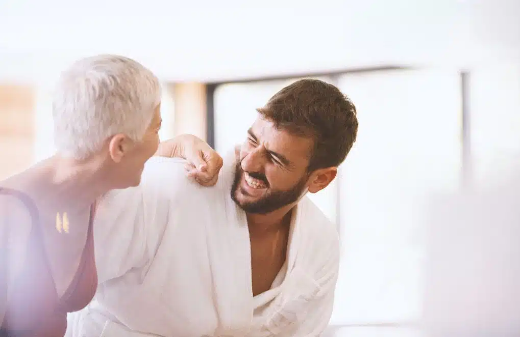 Couple souriant, une femme plus âgée et un homme plus jeune discutant complice dans un café