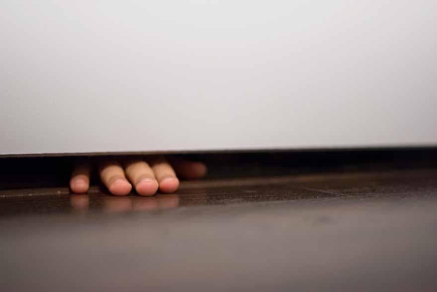 Un enfant qui met sa main sous la porte