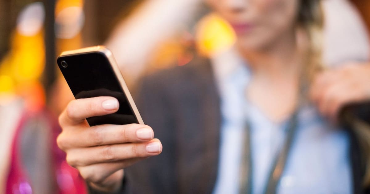 T&eacute;l&eacute;phone portable pos&eacute; sur une table, &eacute;cran allum&eacute; indiquant un appel entrant