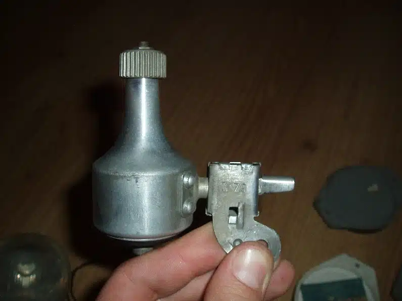 Photo d'une dynamo de vélo vintage, propre, montrant son mécanisme et sa roulette en caoutchouc.