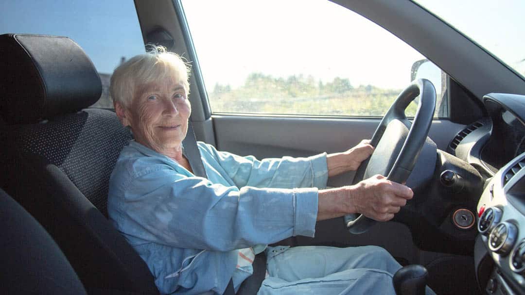 Personne âgée au volant avec panneau d'avertissement