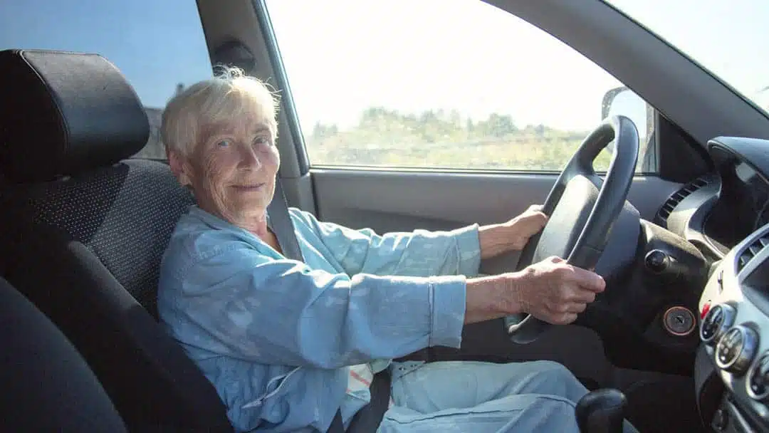 Personne âgée au volant avec panneau d'avertissement