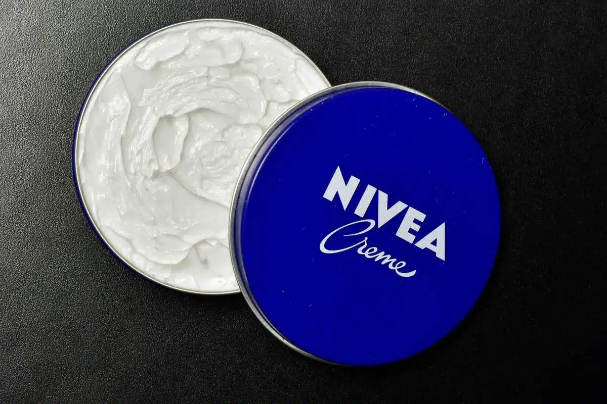 Pot bleu de crème Nivea entouré de fleurs et d'ingrédients naturels