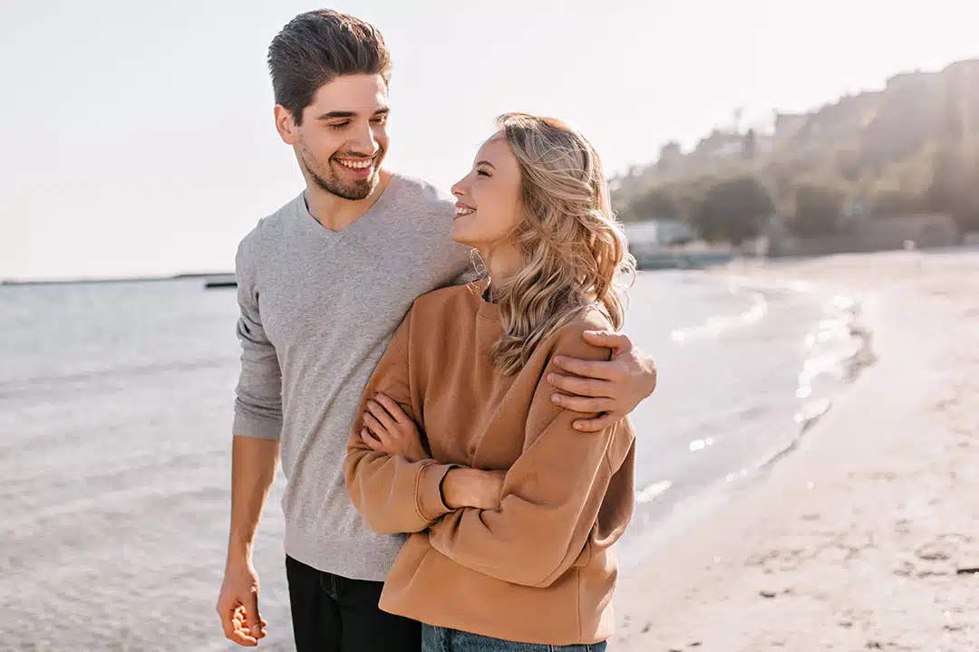 Couple heureux marchant main dans la main sur une plage