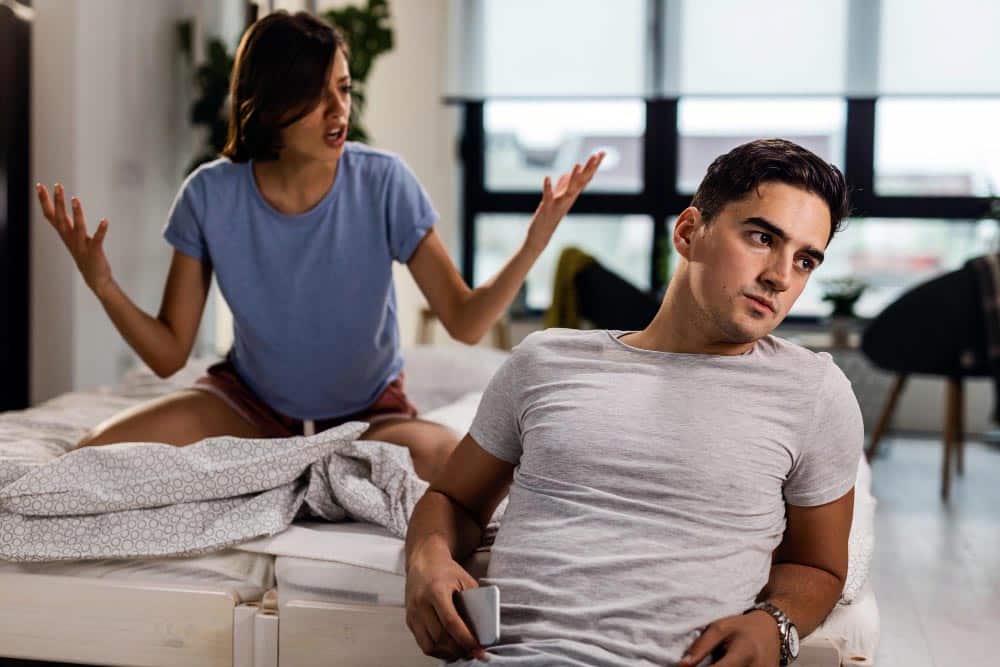 Couple assis à une table, évitant le contact visuel, posture fermée