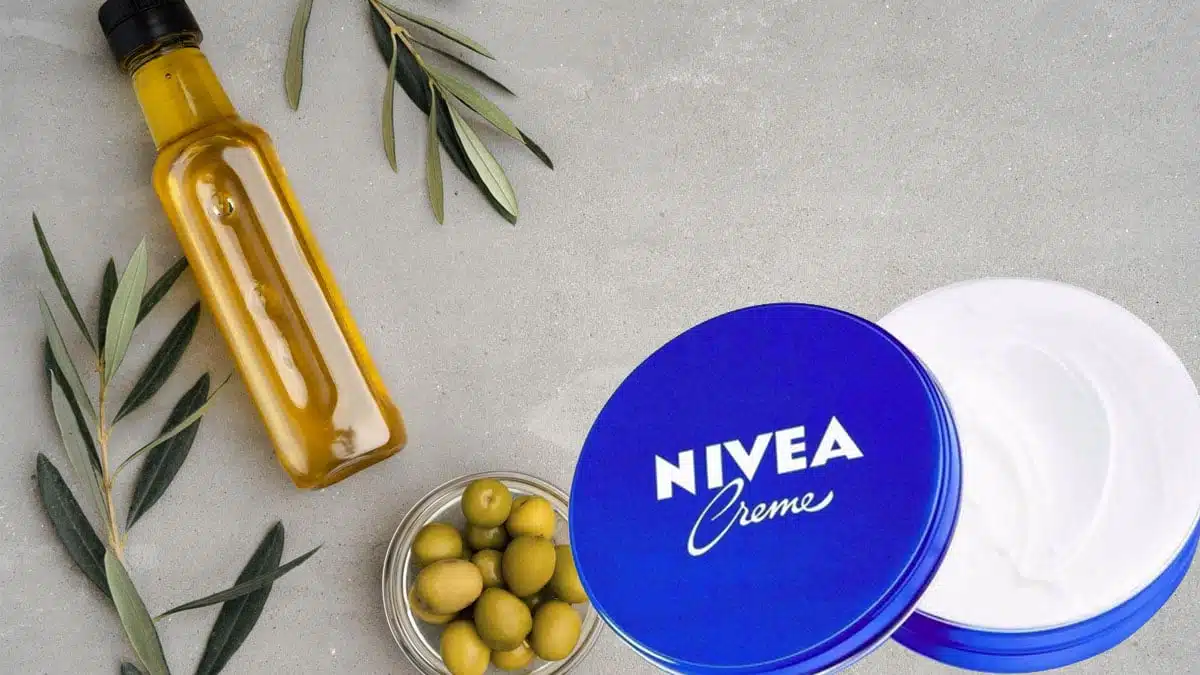 Mains mélangeant de la crème Nivea et de l'huile d'olive dans un bol en céramique