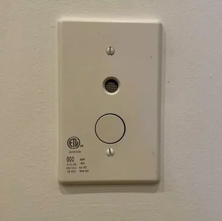 Bo&icirc;tier blanc avec &eacute;cran et trou rond fix&eacute; sur un mur pr&egrave;s d'une piscine