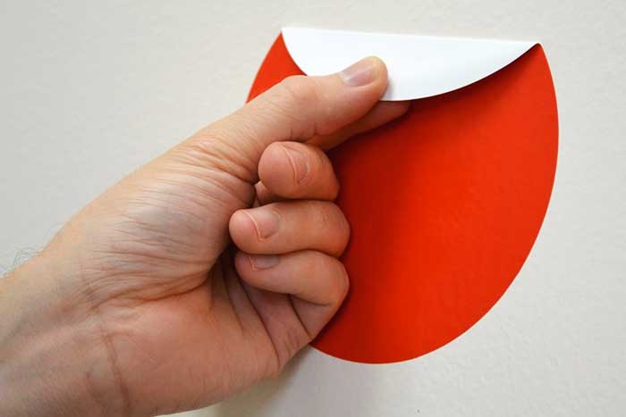 Personne utilisant un s&egrave;che-cheveux pour d&eacute;coller un autocollant sur une vitre de voiture