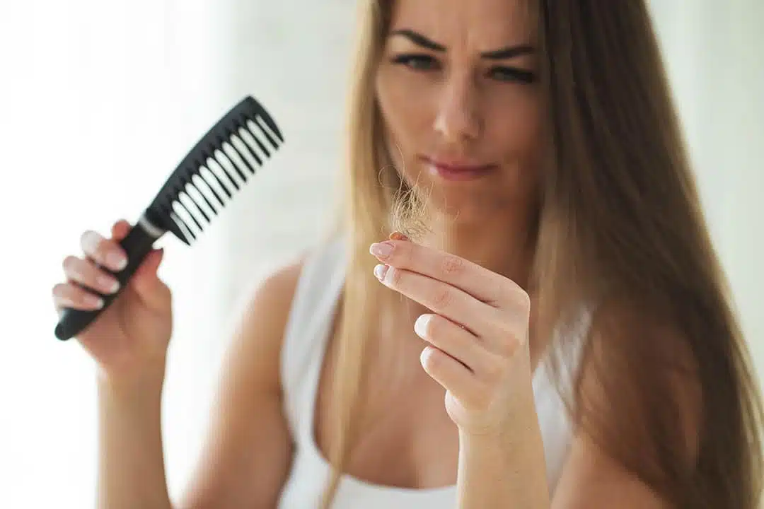 Femme regardant des cheveux restés sur son peigne