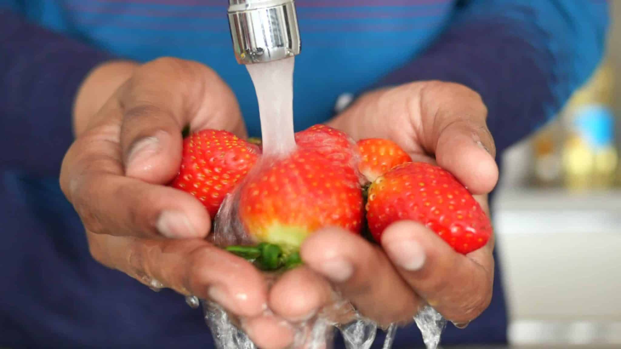 Personne lavant des fraises sous l'eau