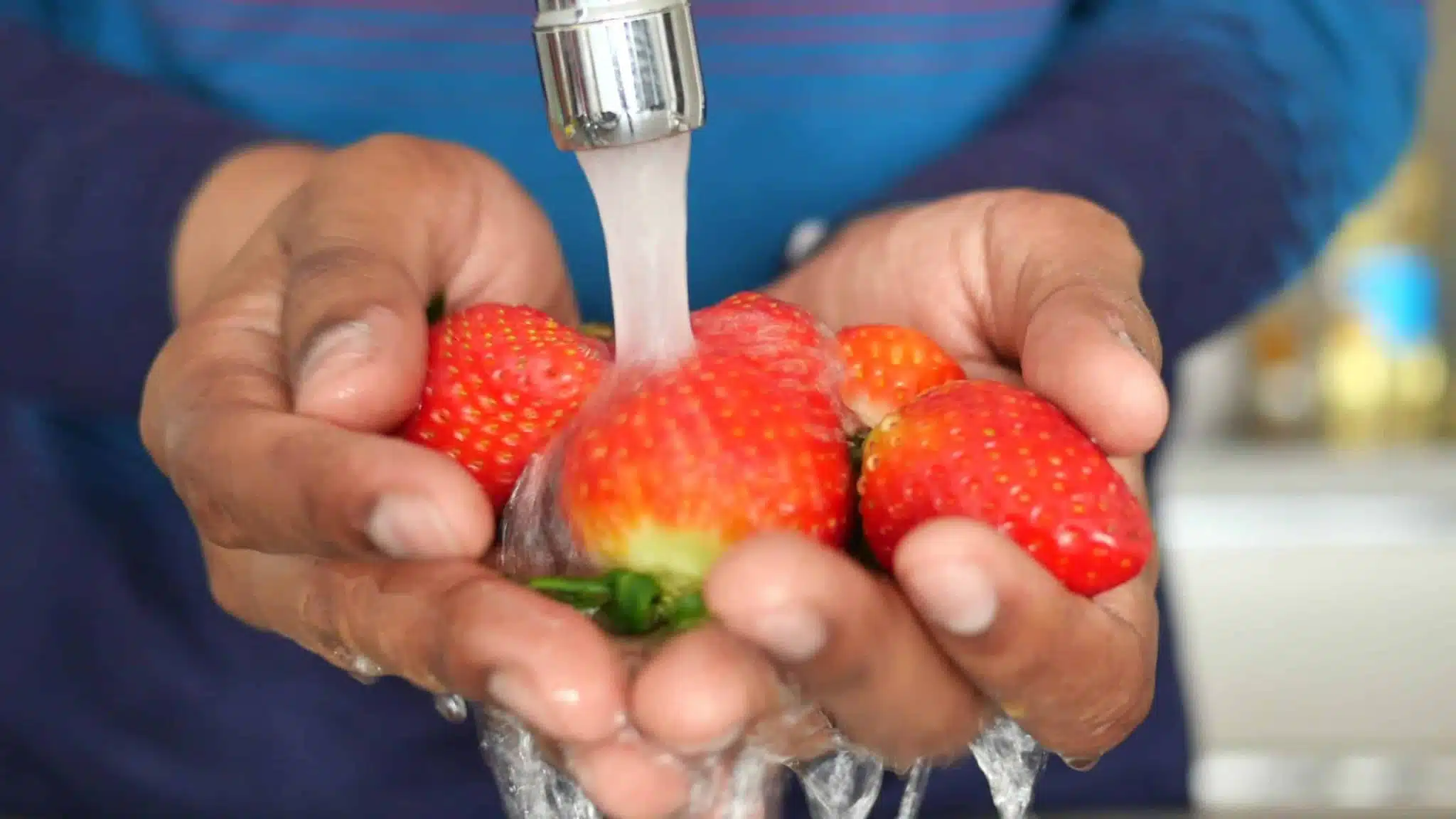 Personne lavant des fraises sous l'eau