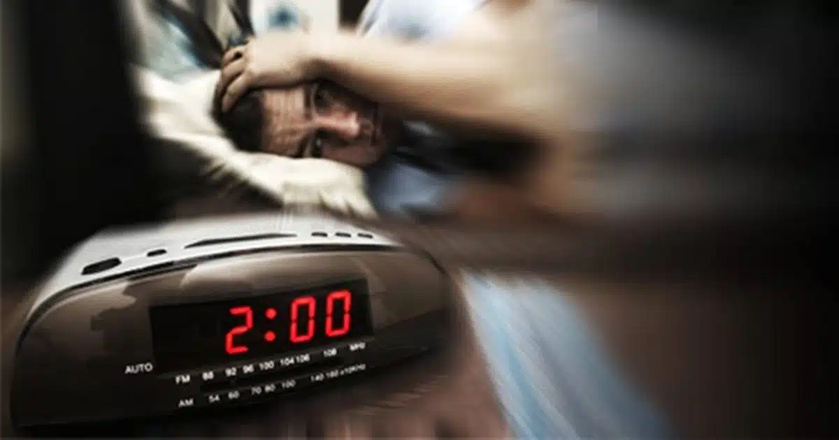 Femme réveillée la nuit regardant par la fenêtre, illustrant les réveils nocturnes et l'état émotionnel