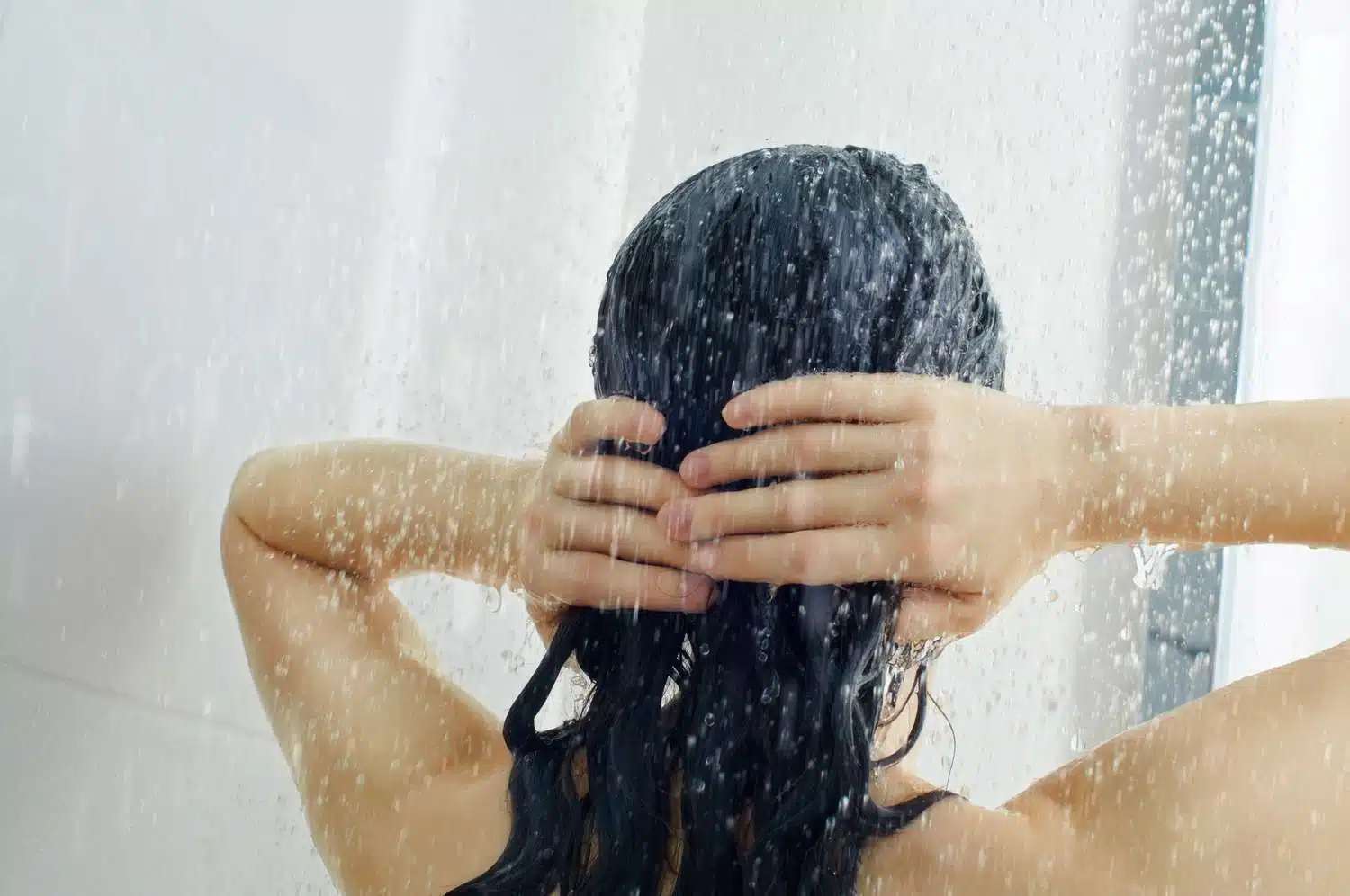Femme se lavant les cheveux sous la douche