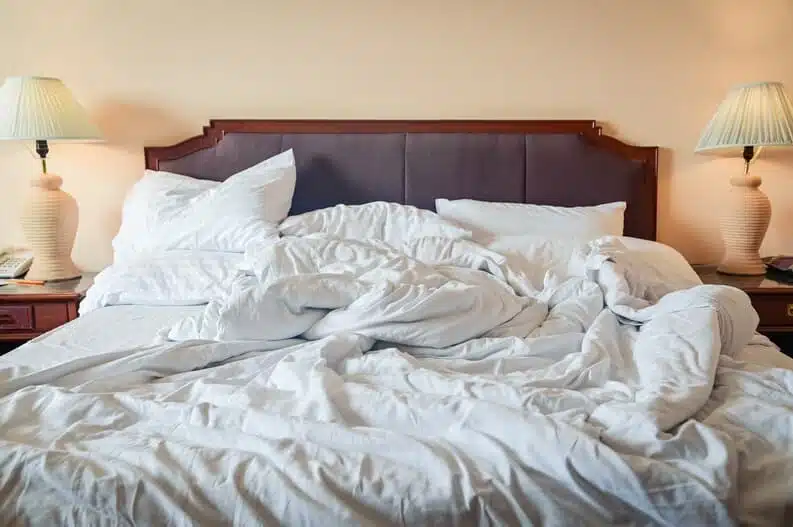 Lit défait avec draps froissés évoquant l'intimité