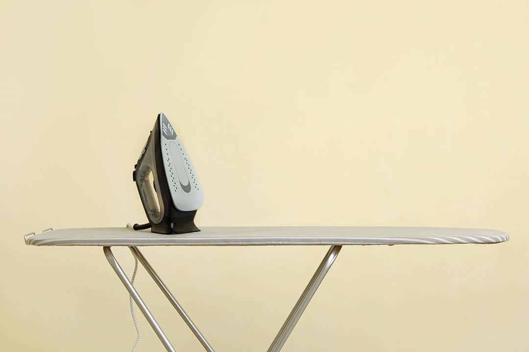 Fer &agrave; repasser moderne pos&eacute; sur une planche &agrave; repasser