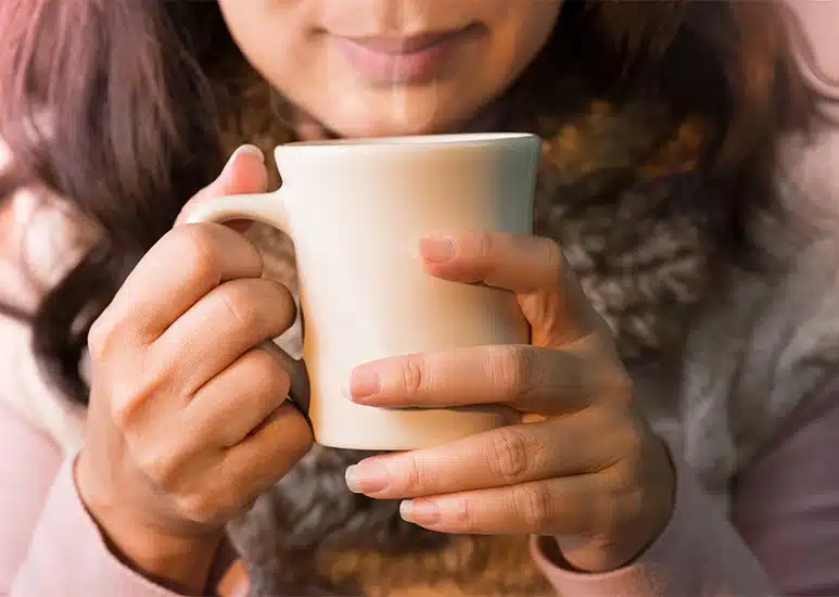 Personne souriante tenant une tasse