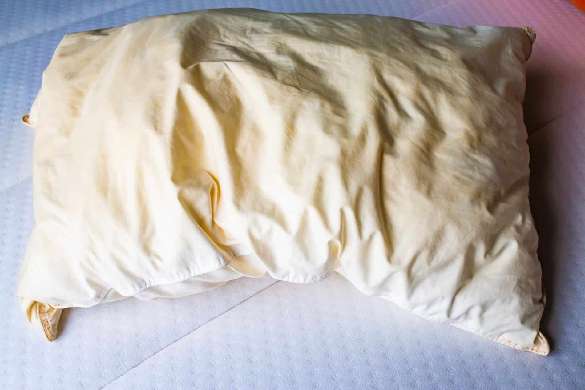 Oreiller blanc pr&eacute;sentant des taches jaun&acirc;tres