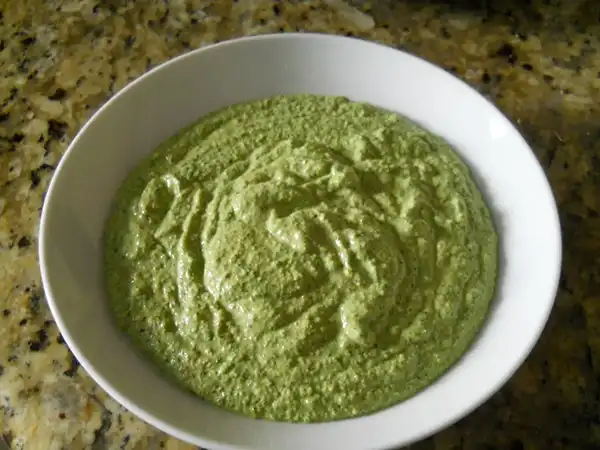 Un bol de pesto vert vibrante au pourpier et basilic, avec des pâtes.