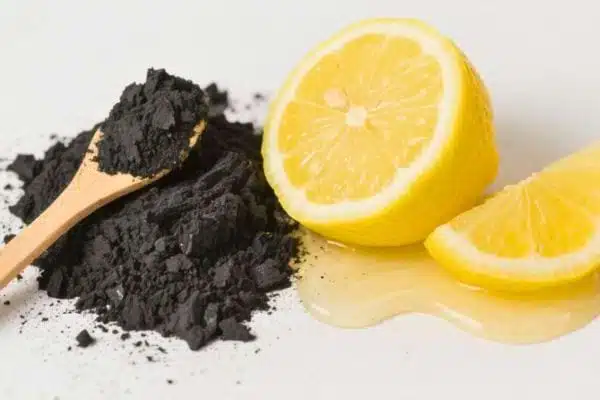 Verre d'eau avec de la poudre de charbon et une rondelle de citron