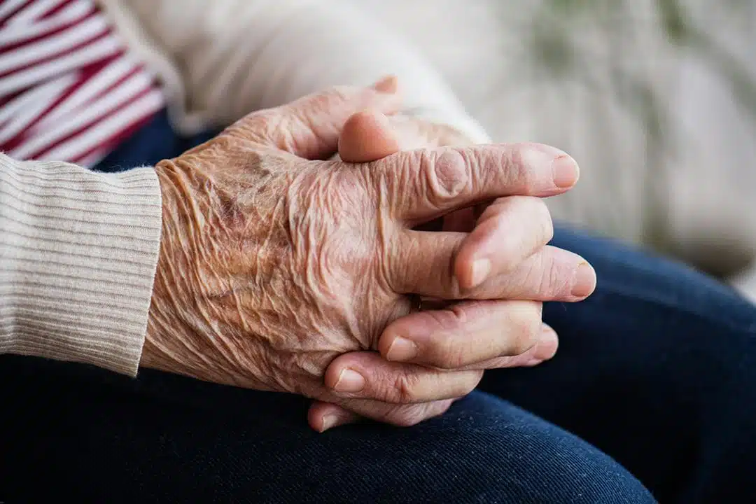 Une personne âgée regardant par la fenêtre d'une chambre lumineuse