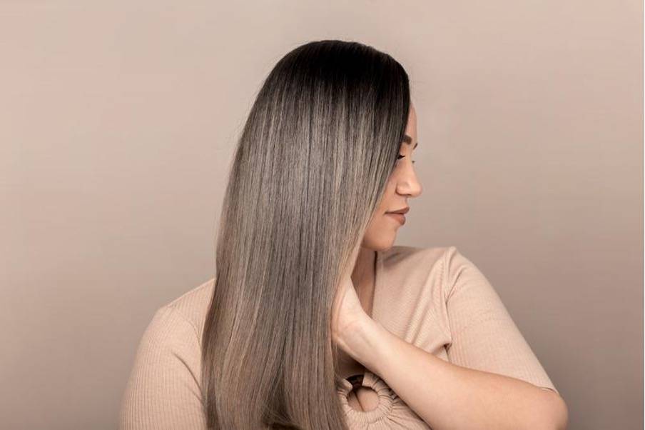 Femme aux cheveux longs et lisses, tenant une bouteille d'huile v&eacute;g&eacute;tale