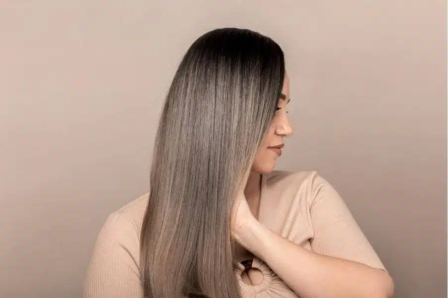 Femme aux cheveux longs et lisses, tenant une bouteille d'huile végétale