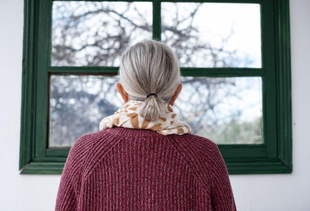 Femme aux cheveux gris regardant par la fenêtre
