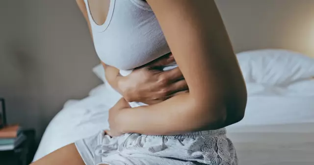 Femme utilisant une bouillotte pour soulager ses règles