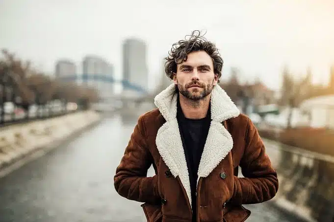 Homme élégant ajustant le bouton de sa manche, mains soignées et posture assurée