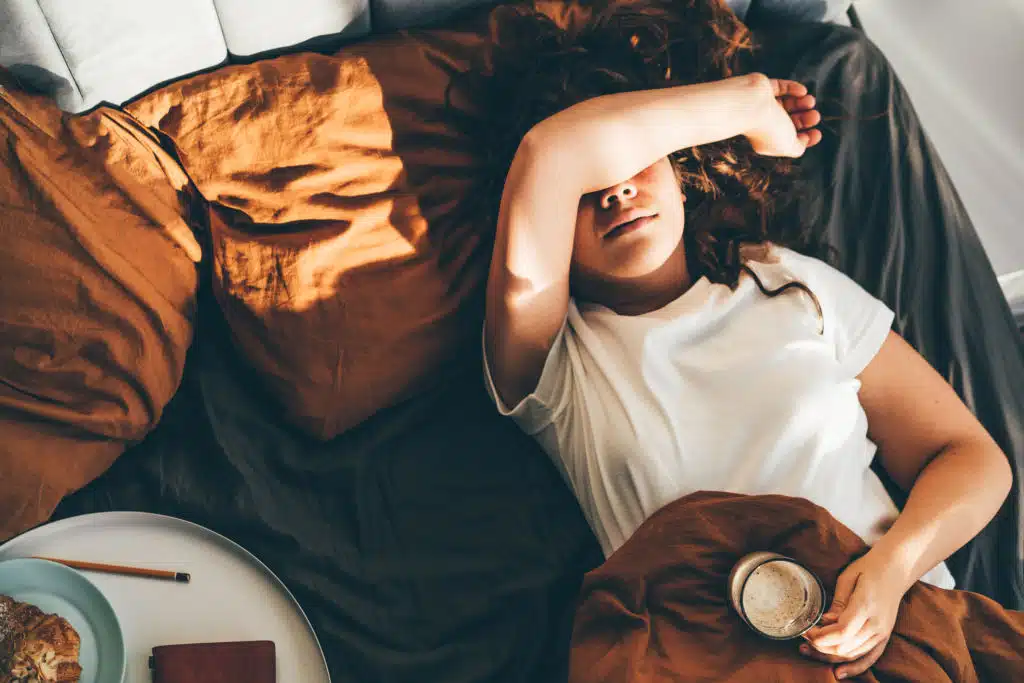 Femme allongée sur un lit, visiblement perturbée