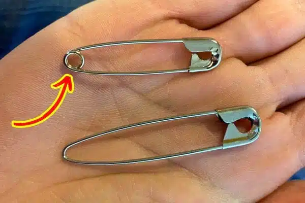 Main tenant une épingle à nourrice pour illustrer son utilisation en couture