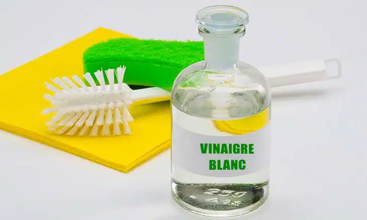 Flacon de vinaigre blanc et chiffon microfibre posés sur une table